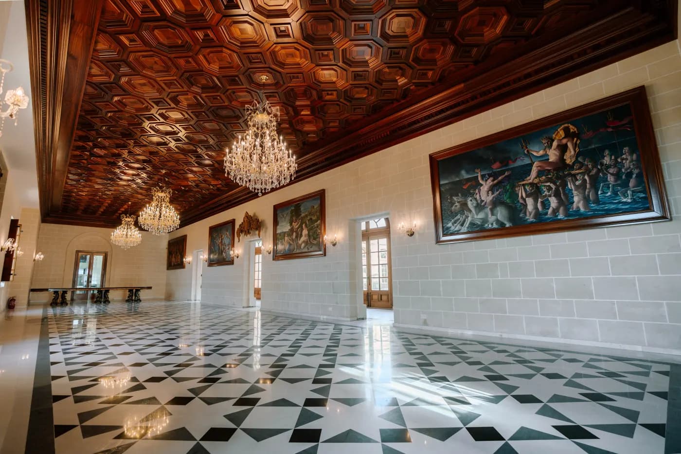 A grand hall hung with paintings beneath a carved timber ceiling